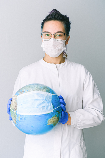 Woman wearing mask and holding globe